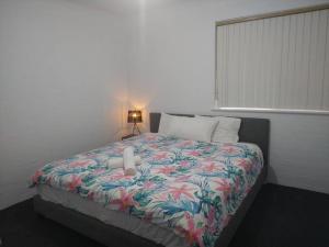 um quarto com uma cama com um cobertor florido em Beautiful Outlook, nr Canberra Hospital @Woden em Phillip