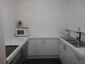 uma cozinha branca com um lavatório e um micro-ondas em Beautiful Outlook, nr Canberra Hospital @Woden em Phillip