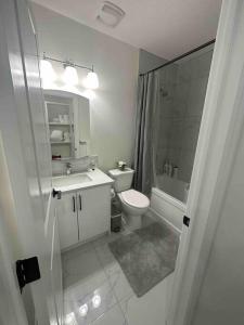 Baño blanco con aseo y lavamanos en Sun Light Kissed Cozy Suite - Modern Boho Paradise en Calgary