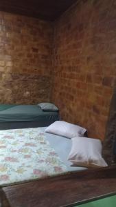 two beds in a room with a brick wall at Big Hostel Brasil in Manaus