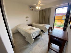a room with two beds and a table and a window at Hotel Daives in Termas de Río Hondo