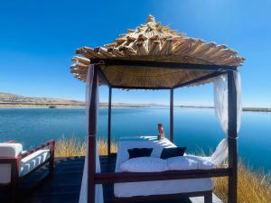 uma cama debaixo de um gazebo ao lado de um corpo de água em Titicaca Ecolodge Perú em Puno