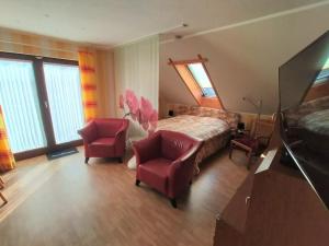 ein Schlafzimmer mit einem Bett und zwei roten Stühlen in der Unterkunft Picturesque Apartment in Neu Lüdershagen with Terrace & Garden in Neu Lüdershagen