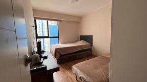 Habitación pequeña con 2 camas y ventana en Apartament Social Tree 907 en Lima