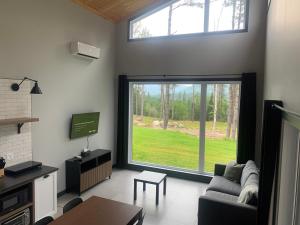 a living room with a large window and a tv at Vallée bras du Nord Jumeau #1 avec spa in Saint-Raymond