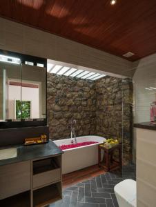 baño con bañera y pared de piedra en 31st December Farms And Estates Munnar en Munnar