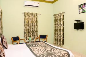 a bedroom with a bed and two chairs at Collection O 4255 Day Night Guest House And Restaurant in Mahāmandir