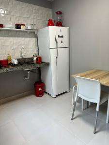 cocina con nevera blanca y mesa en Casa de 2 Quartos no Centro en Marabá