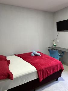 sypialnia z łóżkiem z czerwonym kocem i biurkiem w obiekcie Casa de 2 Quartos no Centro w mieście Marabá