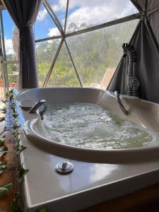 una bañera con dos cucharas delante de una ventana en Refúgio Santa Helena - Domo Safari, en Salesópolis