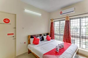 um quarto com uma cama com almofadas vermelhas e uma janela em OYO Flagship 15148 Sky Pix Near Kasi Talkies em Chennai