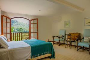 una camera da letto con un letto, due sedie e una finestra di Guest House Fazenda do Francês & Culinária Francesa a Cachoeiras de Macacu Altre 193 foto
