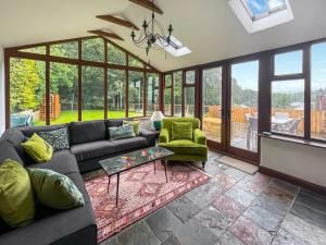 ein Wohnzimmer mit einem Sofa, Stühlen und Fenstern in der Unterkunft The Old Bothy in Watermillock