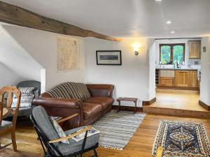 a living room with a leather couch and a kitchen at The Old Bothy in Watermillock