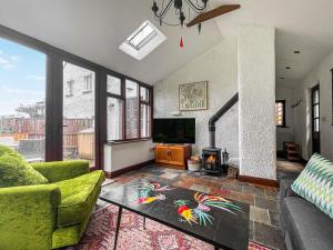 a living room with a green couch and a tv at The Old Bothy in Watermillock