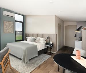 Un dormitorio con una gran cama blanca y una mesa en The Lane Retreat, en Pokolbin