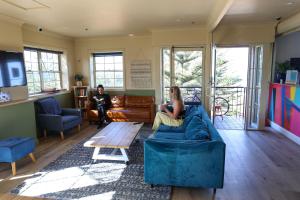 a woman sitting on a couch in a living room at Mad Monkey Coogee Beach in Sydney