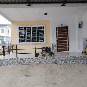 a white house with a window and a stone wall at Ummik Homestay in Tawau