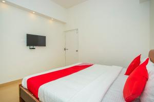 1 dormitorio con 1 cama con almohadas rojas y TV en OYO 18544 Amm Residency, en Bangalore