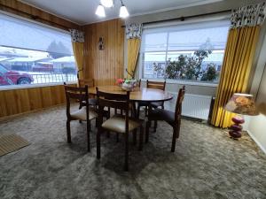 a dining room with a table and chairs and windows at Se arrienda cómoda casa por día in Punta Arenas