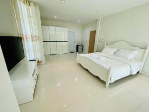 a white bedroom with a large bed and a flat screen tv at Chomdao house98 in Udon Thani