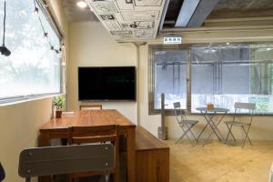 a room with a table and chairs and a tv at WORK INN at Taipei 101 in Taipei