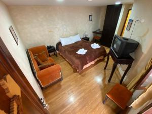 a bedroom with a bed and a tv and a chair at Golden Rest Ecuador in Latacunga