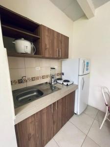 a kitchen with a sink and a white refrigerator at Cómoda Suite cerca de todo in Guayaquil