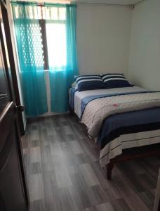 a bedroom with a bed and a window with blue curtains at Hostel Las Vegas in Lima