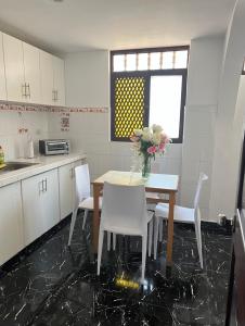 una cocina con mesa y sillas con un jarrón de flores en Hostel Las Vegas, en Lima