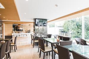 a restaurant with tables and chairs and a large window at twothree a homely hotel - SHA Extra Plus in Bangkok
