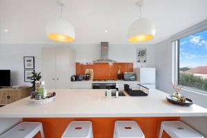 a kitchen with a white counter and orange accents at Silver Ball Retreat in Warrnambool