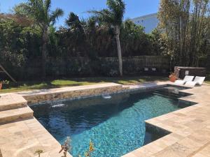 a swimming pool in a yard with a fence at Swansea-by-the-Sea -- Spacious home - heated pool, hot tub, walk to beach! in Ormond Beach