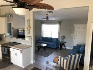a living room with blue couches and a kitchen at Swansea-by-the-Sea -- Spacious home - heated pool, hot tub, walk to beach! in Ormond Beach