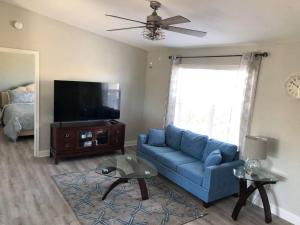 a living room with a blue couch and a flat screen tv at Swansea-by-the-Sea -- Spacious home - heated pool, hot tub, walk to beach! in Ormond Beach
