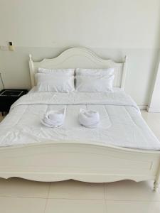uma cama branca com dois sapatos brancos em Chomdao house98 em Udon Thani