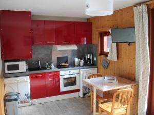 cocina con armarios rojos y mesa de madera en Studio Valloire, 1 pièce, 4 personnes - FR-1-263-525 en Valloire