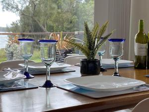 uma mesa com copos de vinho e uma planta sobre ela em Absolute lakefront house - enjoy the sunrise em Budgewoi
