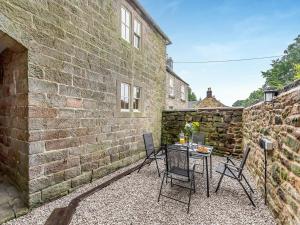 a patio with chairs and a table in front of a building at Manor House Cottage in Highpeak Junction