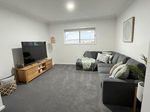 sala de estar con sofá gris y TV de pantalla plana en Surrey View, en Narrawong