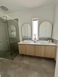 a bathroom with two sinks and a shower and two mirrors at Surrey View in Narrawong