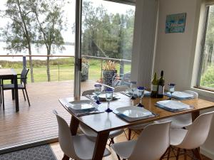 uma mesa de jantar com cadeiras e uma grande janela em Absolute lakefront house - enjoy the sunrise em Budgewoi