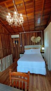 1 dormitorio con cama blanca y lámpara de araña en Casa completa conforto e tranquilidade, en Florianópolis