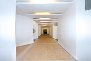 un corridoio di un edificio adibito a uffici con pareti bianche e pavimento piastrellato di Super Capital O Island Inn a Elūr