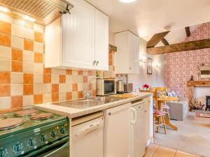 uma cozinha com armários brancos e uma placa de fogão verde. em Foxglove - W43183 em Hawnby