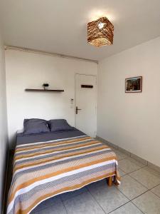 a bedroom with a bed with a striped blanket at L'Escale, appt partagé, shared apartment in Pointe-à-Pitre