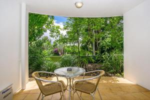 a glass table and two chairs in a room with a patio at Byron Getaway @ Eco Beach in Byron Bay