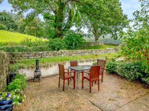einen Tisch und Stühle mit einer Steinmauer in der Unterkunft Bridge Cottage - W43184 in Hawnby