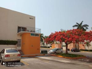 een gebouw met een boom met rode bloemen op een parkeerplaats bij Casa en Renta, RESIDENCIAL OASIS 1,DE XOCHITEPEC, MORELOS. in Xochitepec