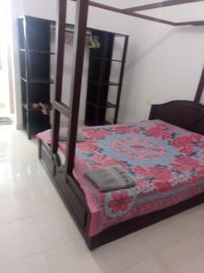 Dormitorio con cama con manta estampada de flores en Heaven Goa Guesthouse, en Benaulim